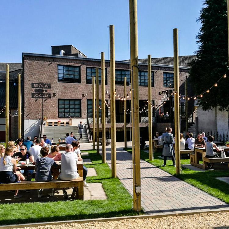 De biertuin met groepen mensen aan picknicktafels in Gulpener Brouwlokaal