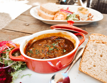 Een bord met een potje zuurvlees, geserveerd met brood en garnering