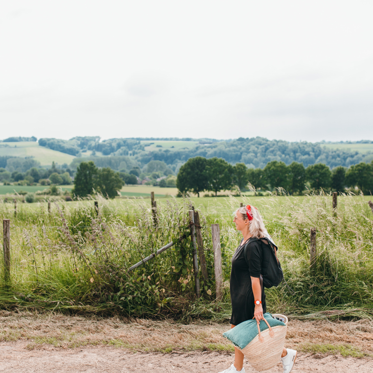 Vrouw wandelend met picknicktas en achterliggend heuvellandschap