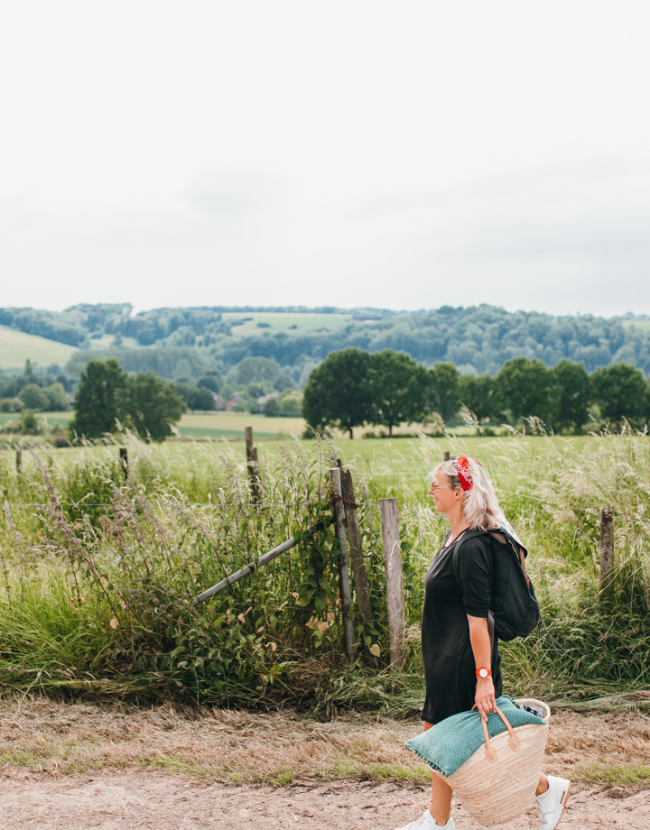 Vrouw wandelend met picknicktas en achterliggend heuvellandschap