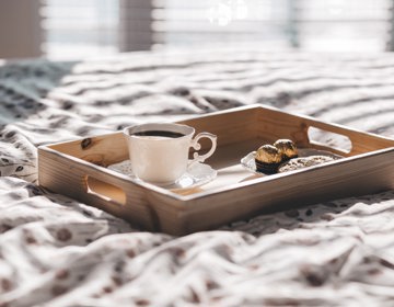 houten dienblad met koffie en bonbons op een hotelbed. 