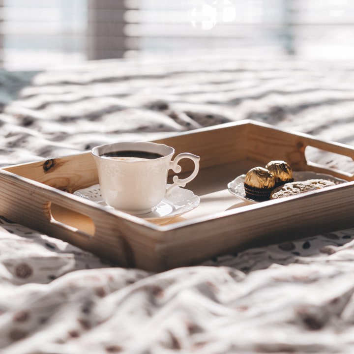 houten dienblad met koffie en bonbons op een hotelbed. 