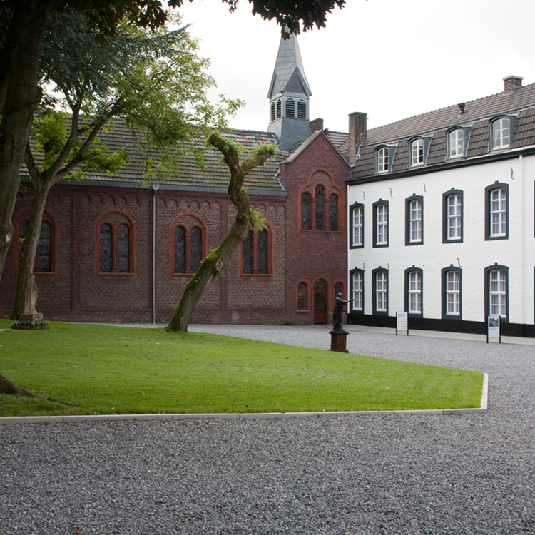 aanzicht van kapel grenzend aan wit landhuis