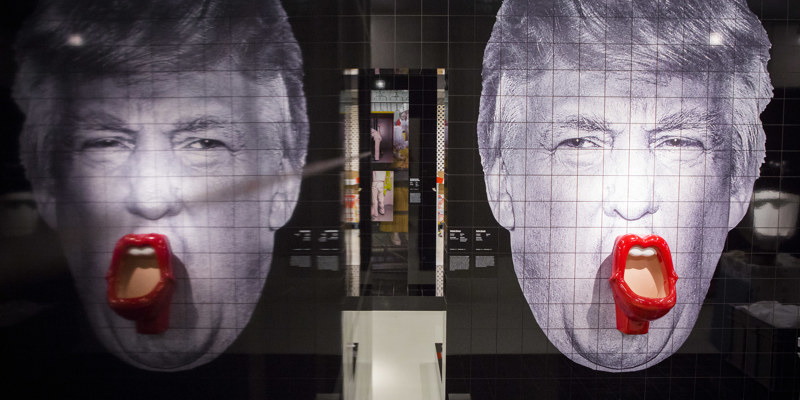 Spiegelbeeld kunstwerk van Donald Trump gemaakt uit sanitairtegels waarbij de mond een met rode lippen omlijste pisbak is