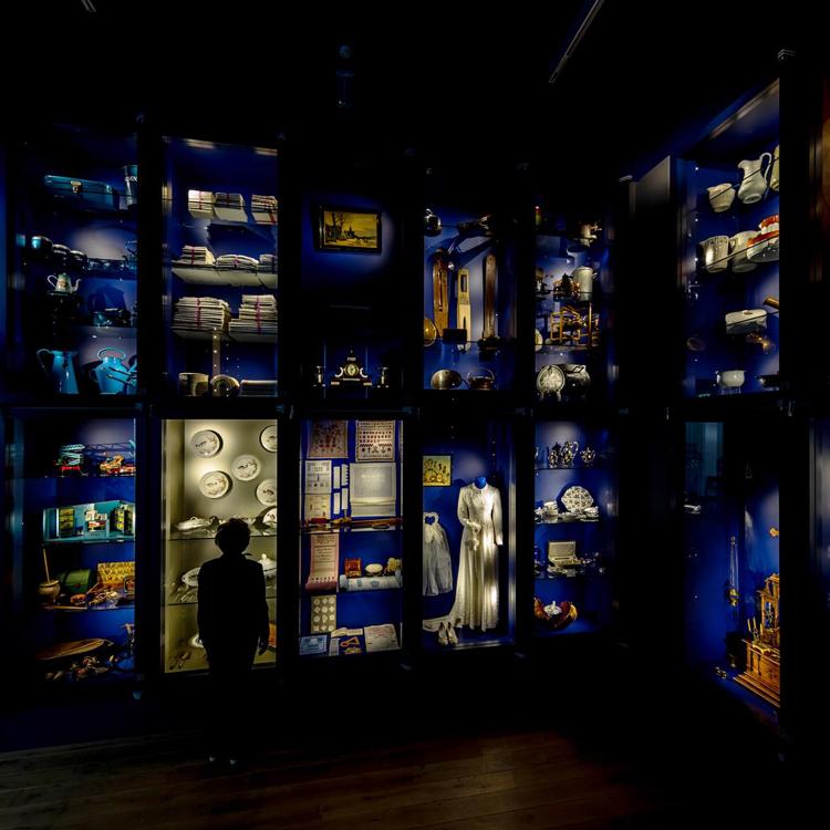 donkere foto van blauw verlichte vitrinekasten waarin spullen staan uitgestald