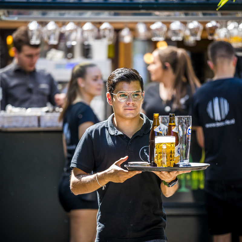 Een ober die drank uitserveerd op het terras van het Hijgent Hert in Vijlen