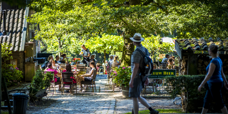 Wandelaars die langs het terras van het Hijgent Hert lopen