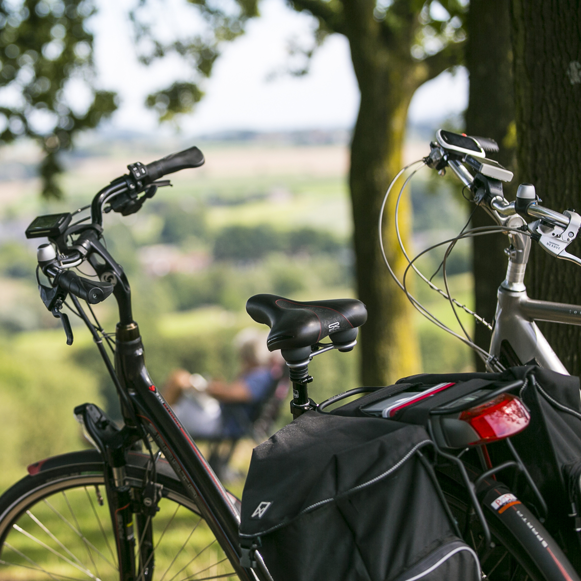 Close up van twee fietsen met op de achtergrond twee mensen op een bankje die genieten van het uitzicht