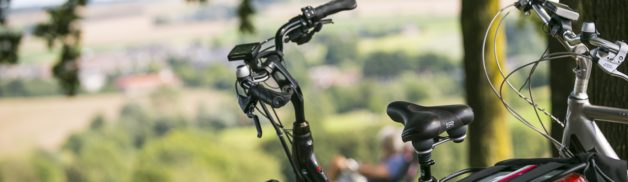 Close up van twee fietsen met op de achtergrond twee mensen op een bankje die genieten van het uitzicht