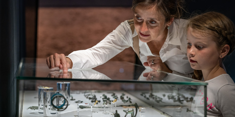 Mevrouw met kindje bekijken een vitrine met Romeinse vondsten in het Romeins Museum Heerlen