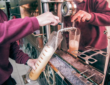 Iemand tapt bier in een grote maatbeker