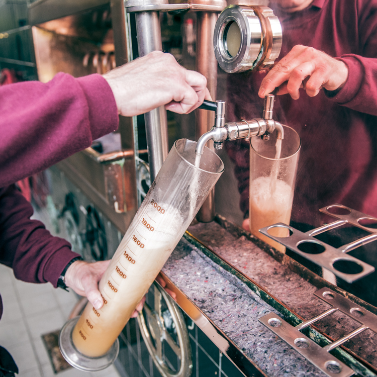 Iemand tapt bier in een grote maatbeker