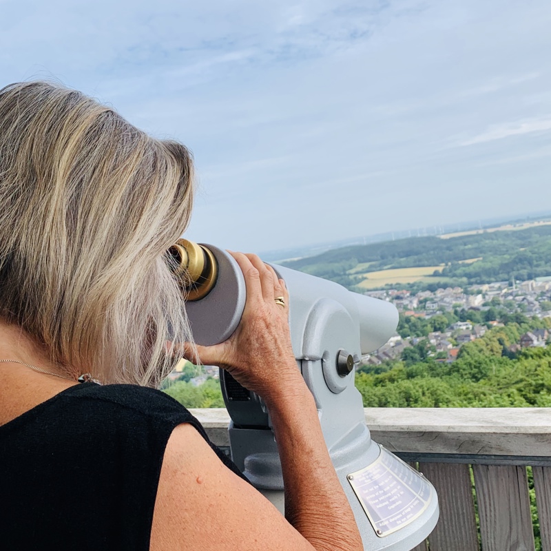 Bezoeker die door de verrekijker kijkt vanaf het panorama dek van de uitkijktoren bij het drielandenpunt in Vaals
