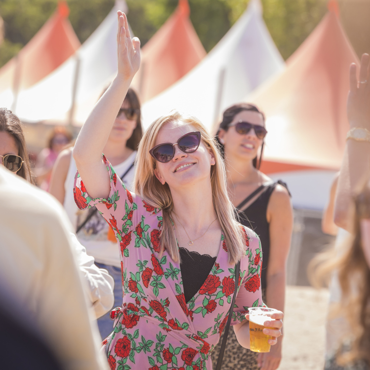 Doorkijkje naar blonde dame feestvierend op festival met biertje in haar hand