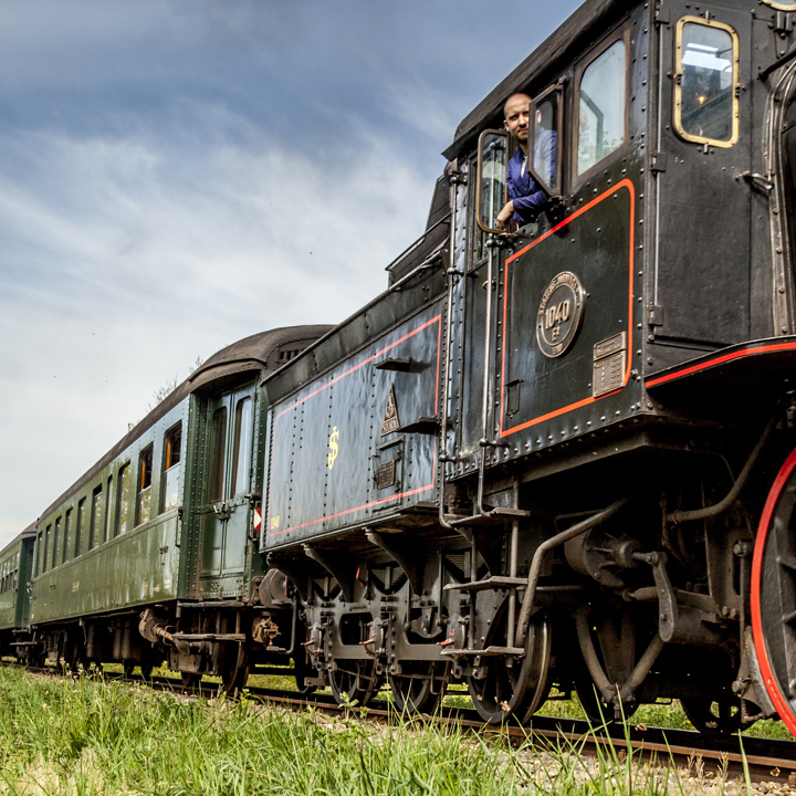 Zicht op de Miljoenenlijn Stoomtrein locomotief en treinstellen. Uit locomotief hangt de machinist. 