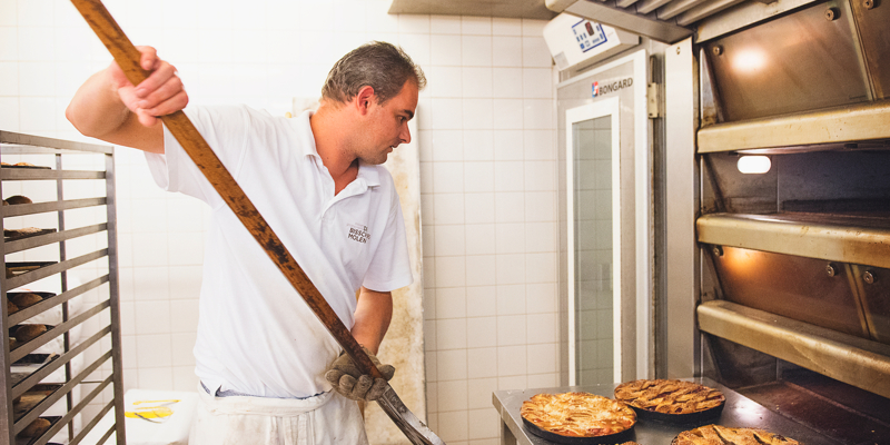 Een bakker schept verschillende linzenvlaaien uit zijn oven