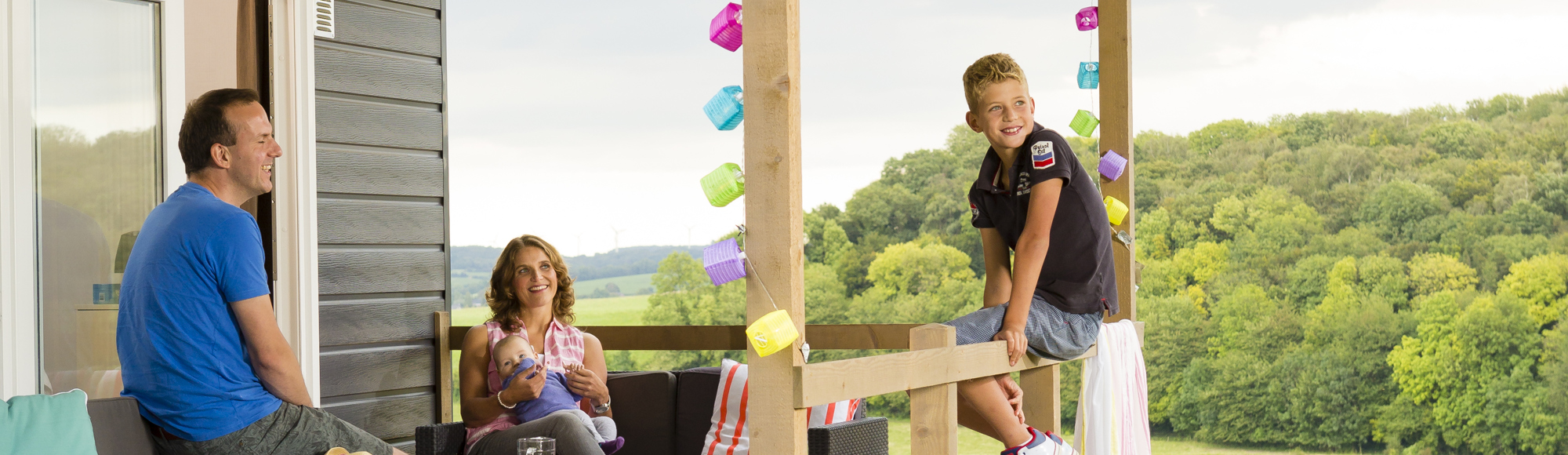 Gezin zit buiten te genieten van het uitzicht bij Glamping camping Gulperberg