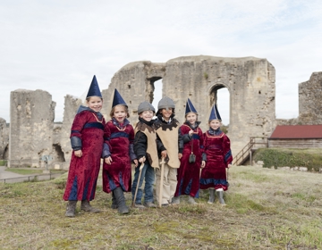 Groep kinderen staan verkleed boven op de kasteelruine in Valkenburg