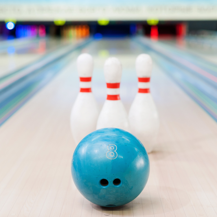 Een bowlingbal met drie kegels gepositioneerd vooraan de bowlingbaan