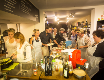 Een groep mensen is druk bezig in de keuken tijdens een kookworkshop