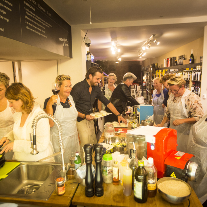 Een groep mensen is druk bezig in de keuken tijdens een kookworkshop