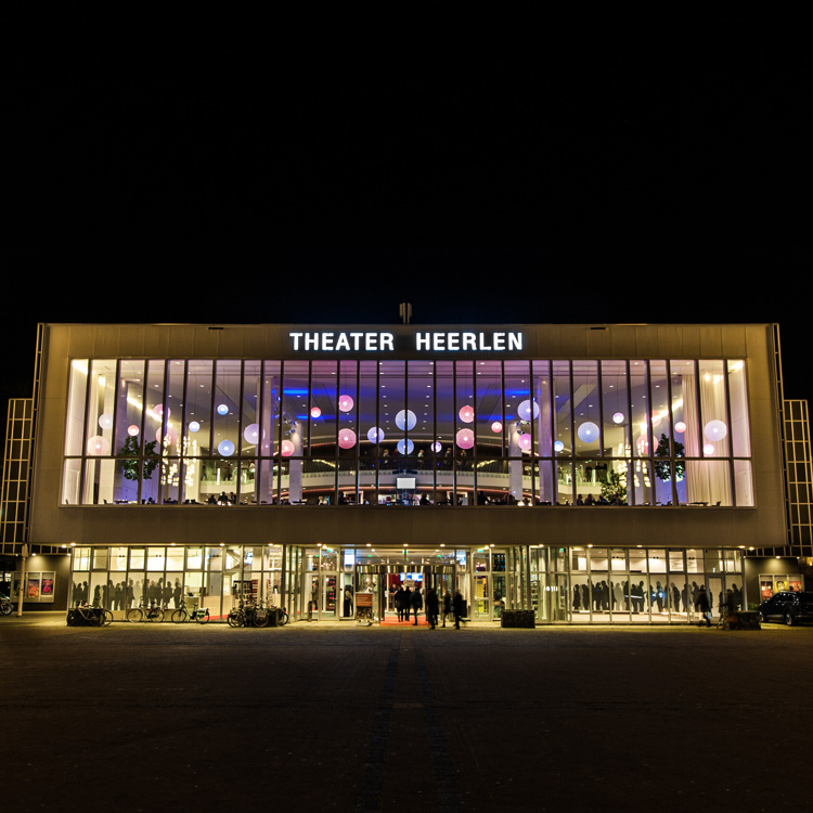De voorkant van Parkstad Limburg Theater Heerlen verlicht op een donkere avond