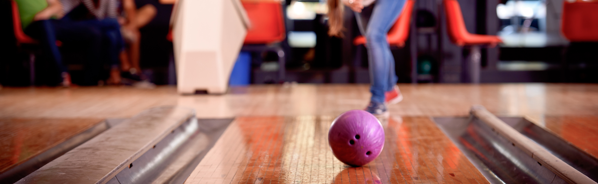 Een vrouw gooit een paarse bowlingbal 