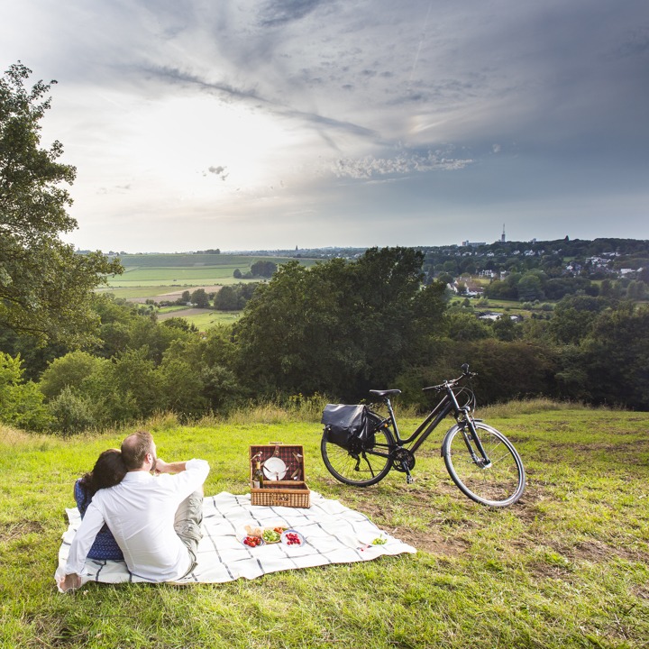 Een koppel op een picknickdeken kijkt uit over het heuvellandschap