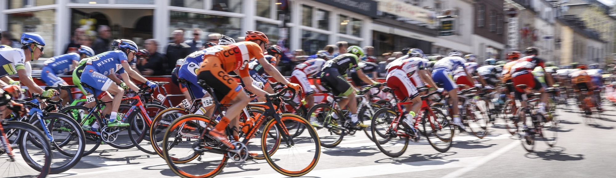 Het peloton van de Amstel Gold Race fiets door een bocht richting de Cauberg