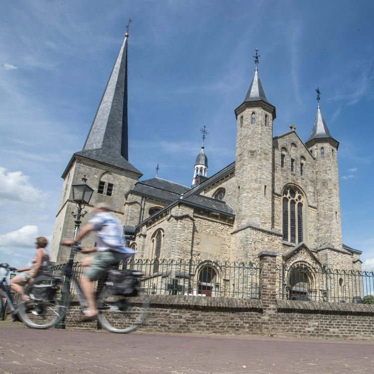 Twee fietsers fietsen langs een kerk