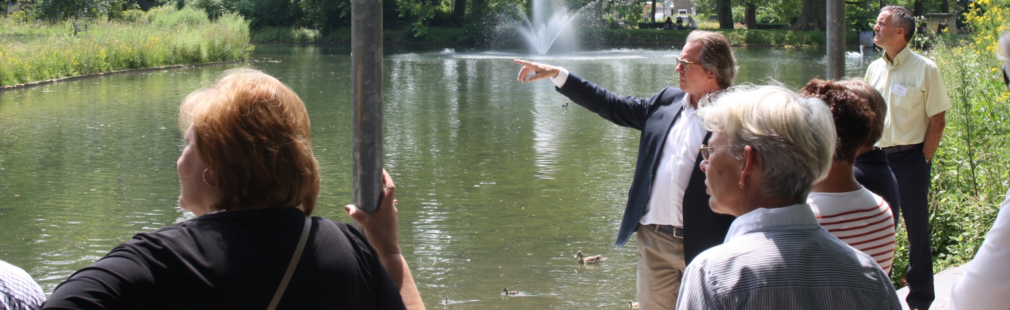 Een gids geeft een rondleiding aan een groep mensen in het Proosdijpark in Meerssen