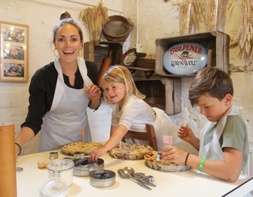 Vrouw en twee kinderen bakken een vlaai bij de Bisschopsmolen