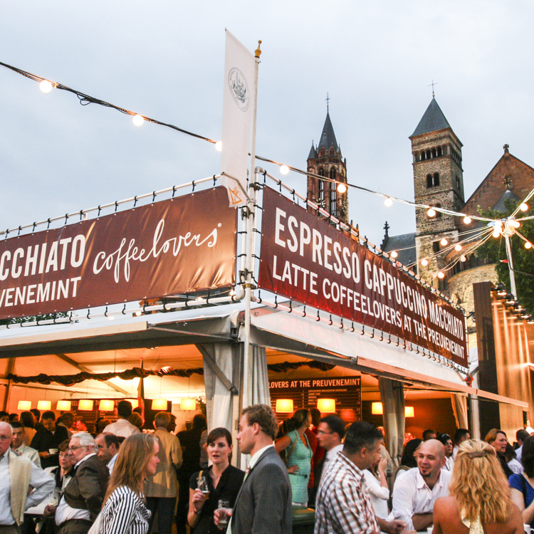 De Preuvenemint kraampjes worden druk bezocht door veel mensen met op de achtergrond de kerk op het Vrijthof