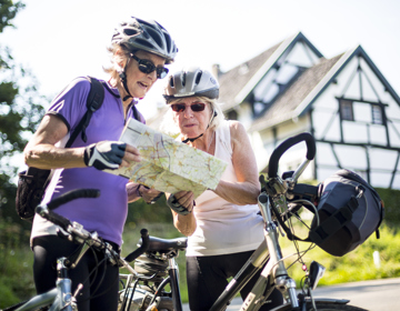 Twee dames kijken op een fietsknooppuntenkaart voor een vakwerkhuis