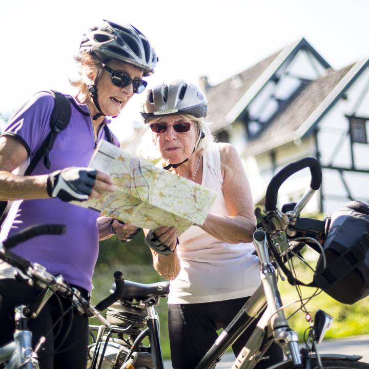 Twee dames kijken op een fietsknooppuntenkaart voor een vakwerkhuis