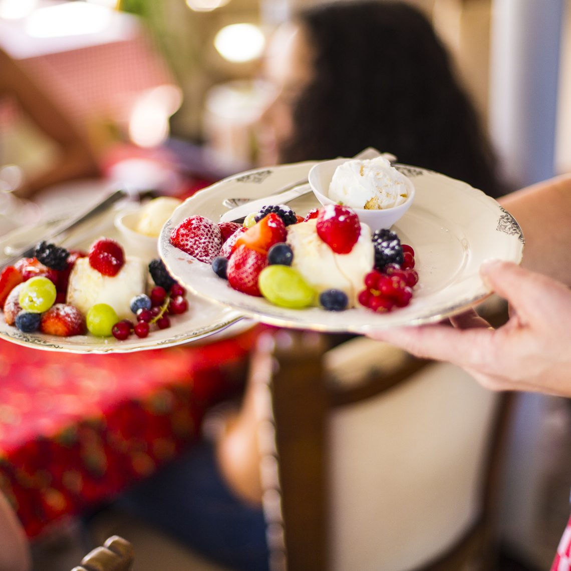 Iemand serveert twee borden met ijs en vers fruit