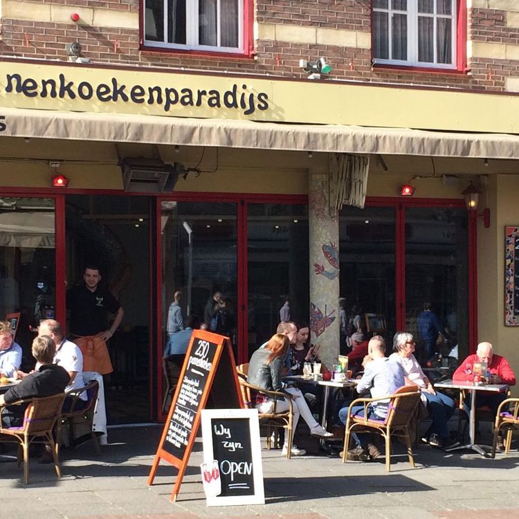 Een drukbezocht terras aan de straatkant van een Pannenkoekenparadijs