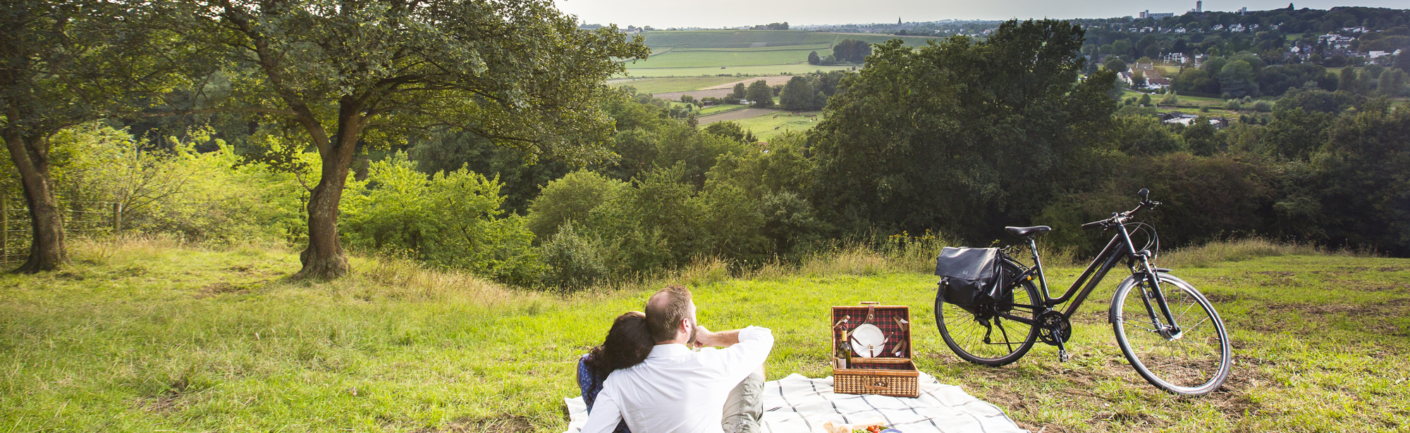 Koppel zit op een deken te picknicken en kijkt uit over het landschap 