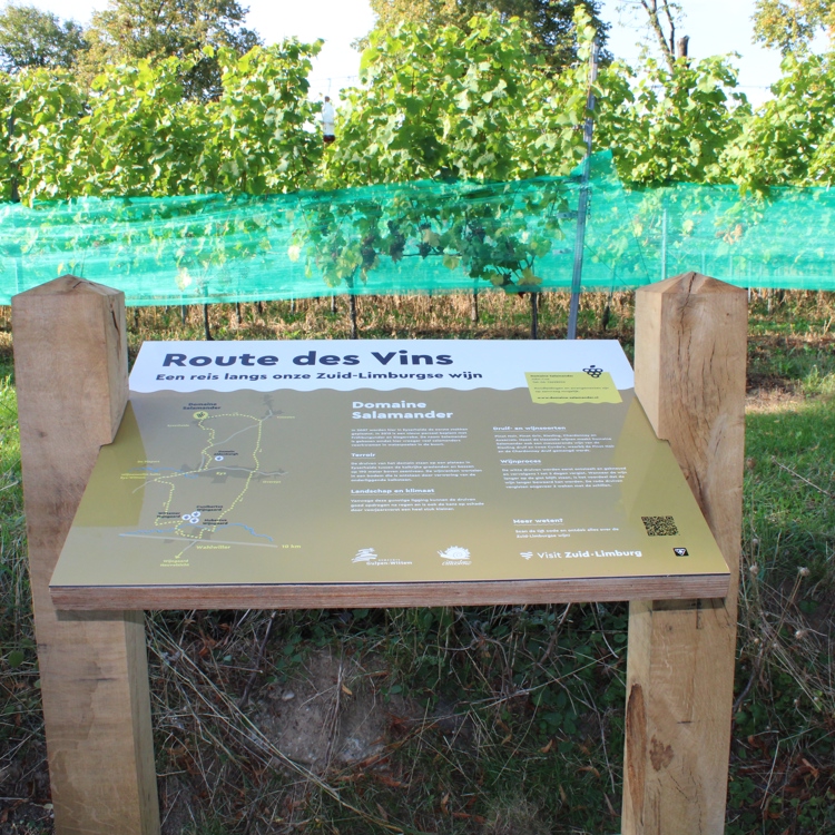 Het wijnbord van Domaine Salamander gesitueerd voor de wijnranken, die met groene bescherming zijn afgedekt