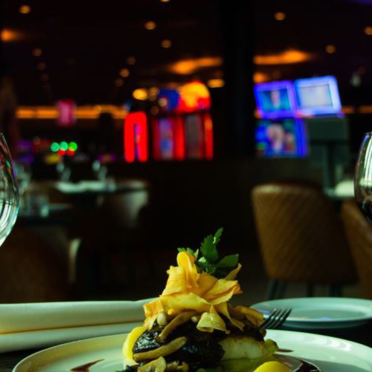 Een pasta en wijnglazen geserveerd aan een tafel met op de achtergrond een casino