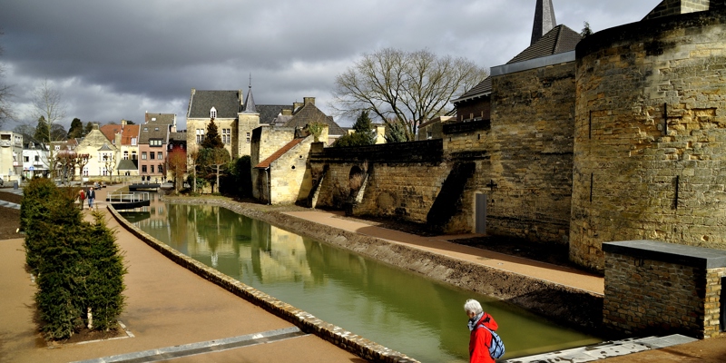 Halerpark met oude stadswal en gracht in Valkenburg. Persoon loopt op de voorgrond