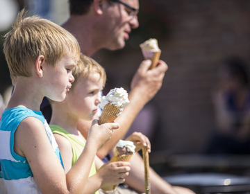 Twee jongens en hun vader genieten van een ijsje op een hoorntje
