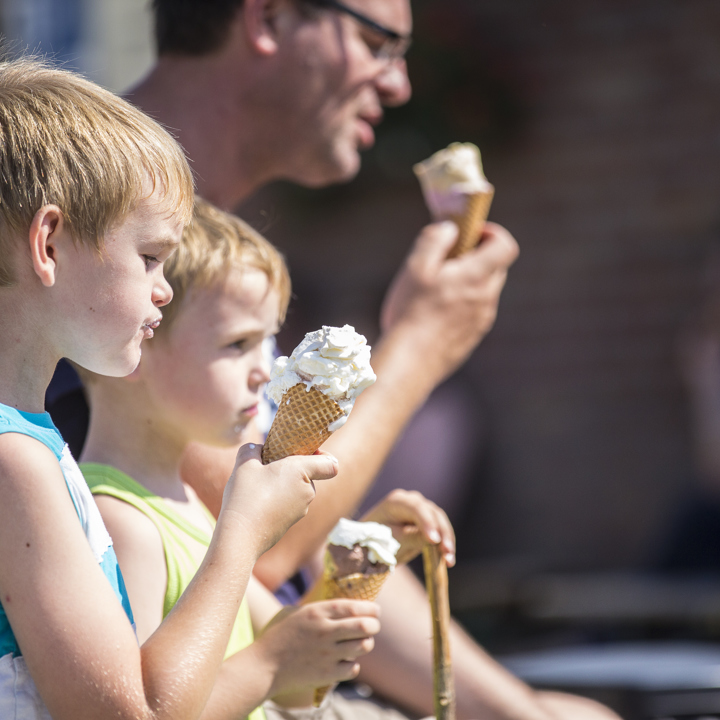 Twee jongens en hun vader genieten van een ijsje op een hoorntje