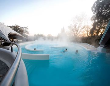 Thermaal buitenbad met stroomversnelling bij wellnesscentrum, waar de damp van het water afkomt.