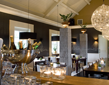 Interieur van een restaurant met sfeervolle kaarsjes en een grote wijnkoeler op de bar. 