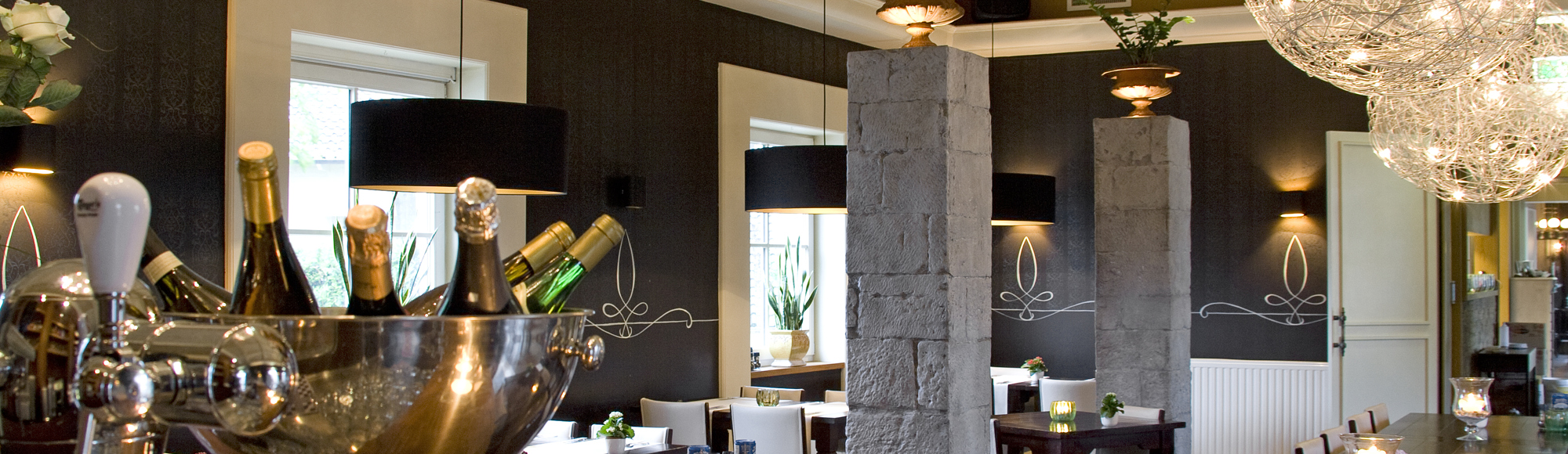 Interieur van een restaurant met sfeervolle kaarsjes en een grote wijnkoeler op de bar. 