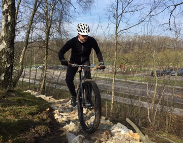 Mountainbike op kiezelpad aan bosrand naast weg