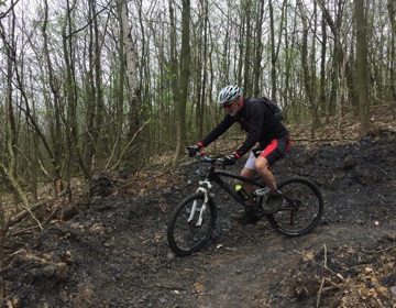 Een mannelijke mountainbiker maakt een scherpe bocht tijdens een afdaling in het bos