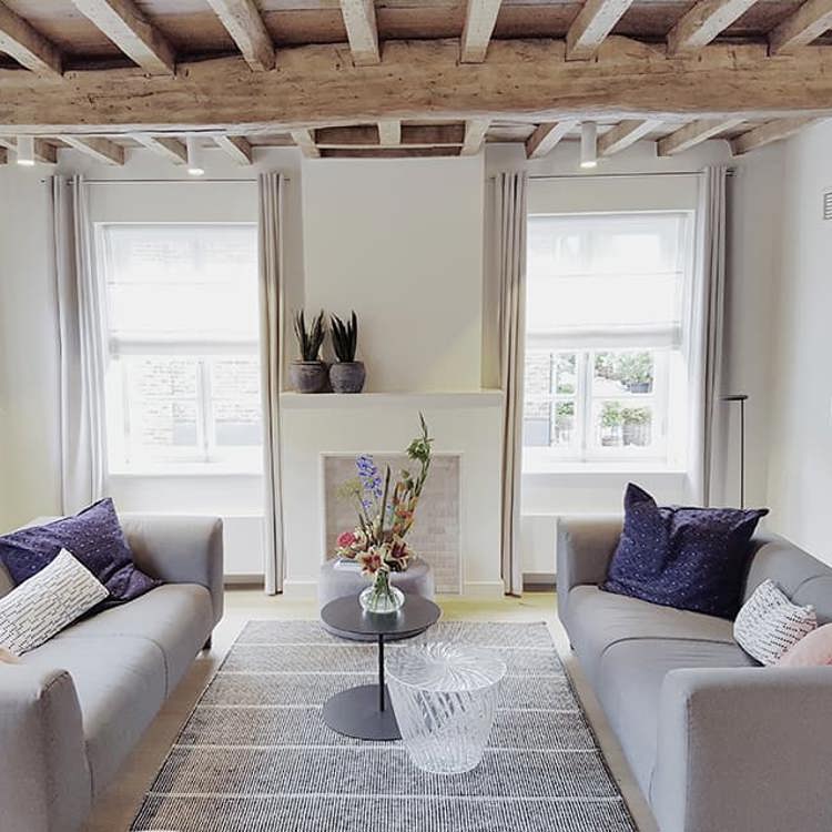 Interieur met twee banken in lichte kleuren en een houten plafond. 