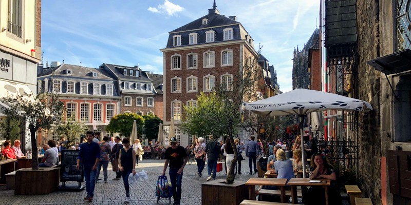 Mensen lopen over het marktplein en zitten op het terras in Aken